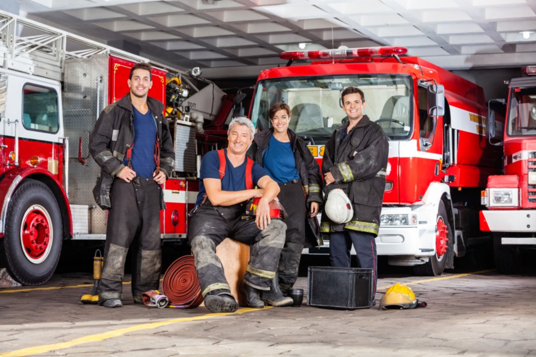 Firemen and women posing with trucks behind